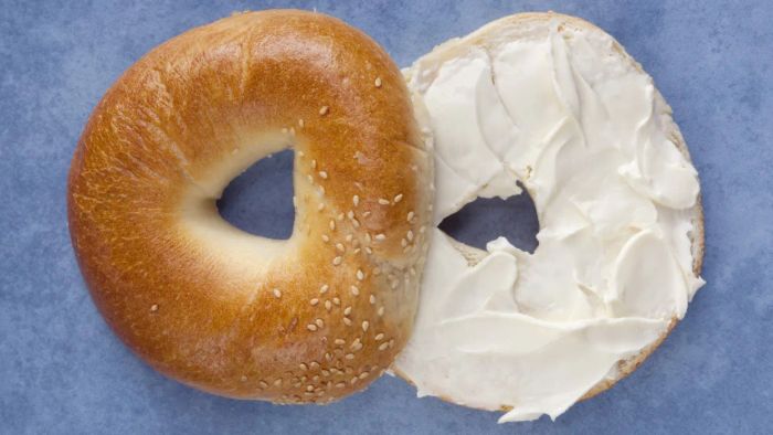 A bagel, sliced in half with cream cheese spread in the middle.
