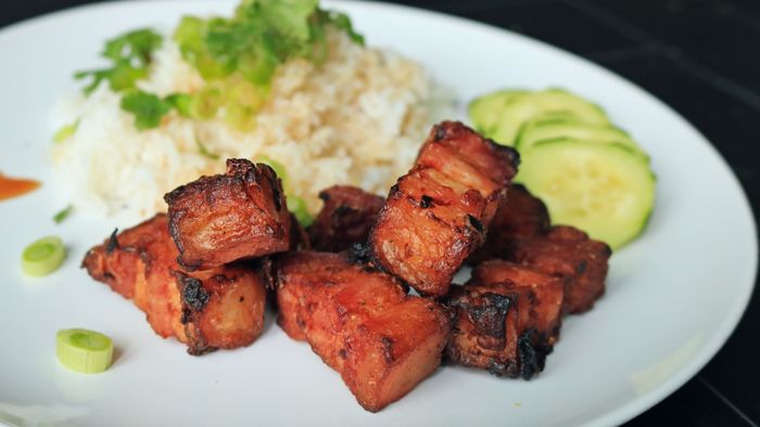 Savory chunks of tender pork belly served alongside a bed of rice.