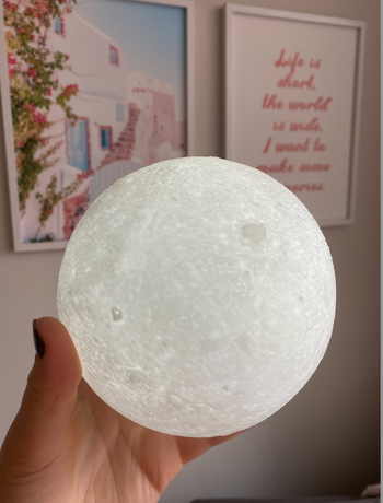 An editor holding a small moon that is lit up in their hand.