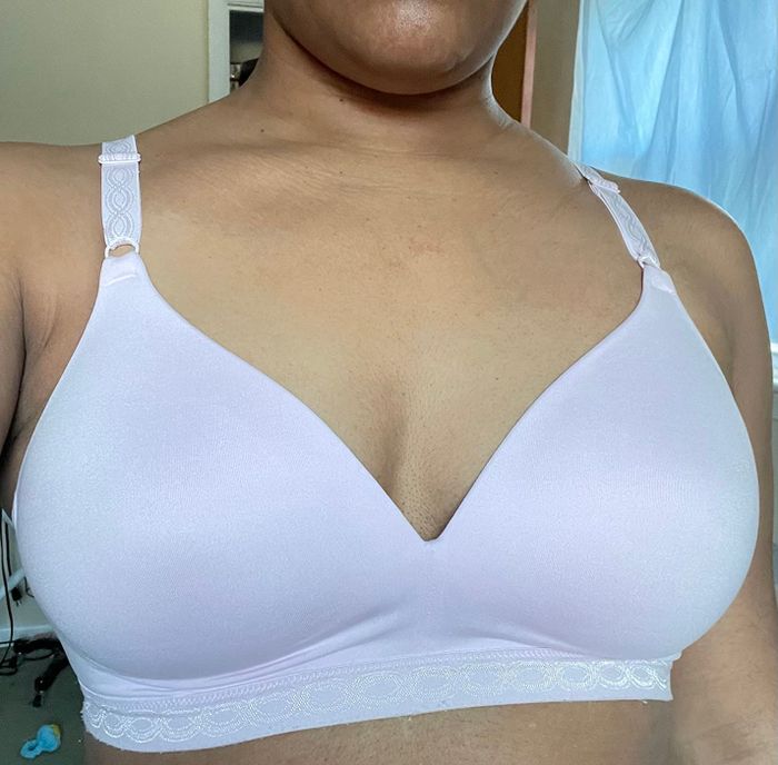 A person wearing a soft, seamless bra with thin straps, relaxing in a cozy bedroom setting.
