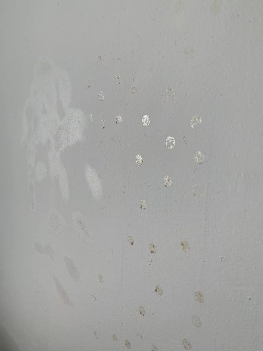 A before photo showing a wall covered in stubborn sticky residue from labels