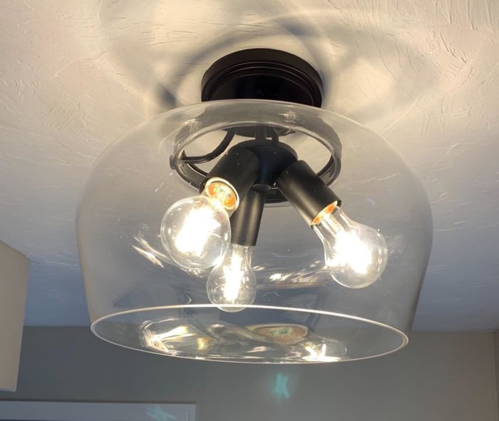A dirty light fixture with three light bulbs