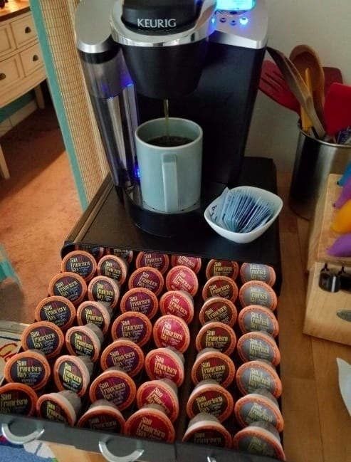 A black drawer beneath a Keurig machine, neatly organizing various K-Cups.