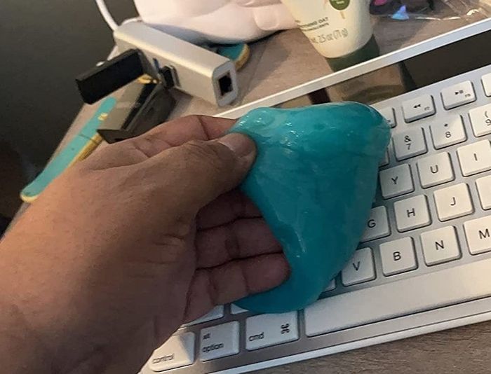 A reviewer applies blue putty to a computer keyboard.