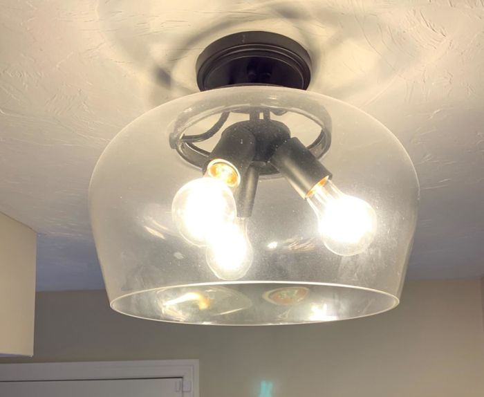 A dirty light fixture with three light bulbs