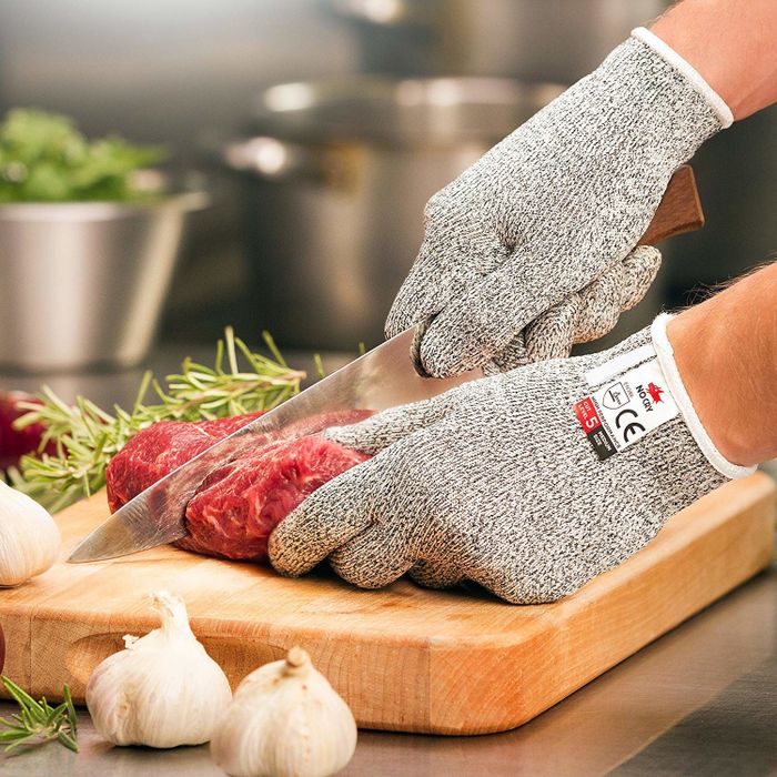A model wearing grey gloves while preparing meat in the kitchen.