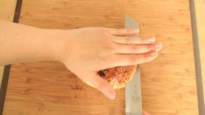 A hand holding a bagel, viewed from above