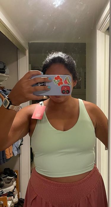 A person in a sleeveless top and skirt takes a mirror selfie in a closet area, showing off their outfit.