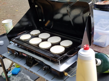 Small, round pancakes cooking on a griddle.