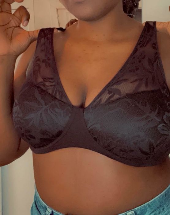 A person is dressed in a lace-patterned bra paired with denim bottoms. Their face is not visible in the shot.