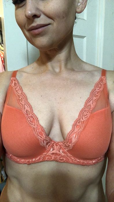 A reviewer models the orange bra.