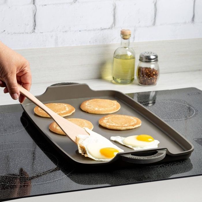 The double-burner griddle is cooking pancakes and eggs.