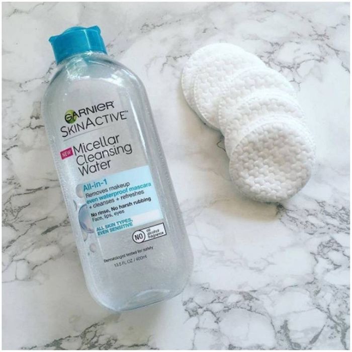 The micellar water placed next to cotton pads.