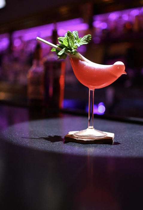 a martini glass designed to resemble a bird, with the drinking opening at the tail of the bird