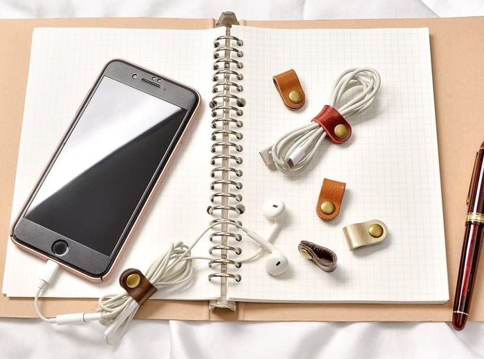 An open notebook with simple ties neatly wrapped around earbud cords