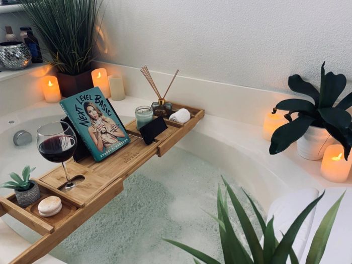 Reviewer’s bathtub tray resting on the tub, holding a book, wine, candle, and plants