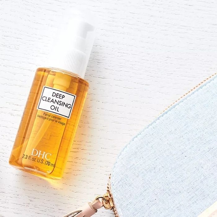 A bottle of DHC Deep Cleansing Oil placed beside a cosmetic bag.