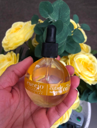 A hand of the reviewer gently gripping a bottle of cuticle oil