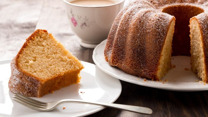 A piece of bundt cake sits on a plate beside the whole cake.