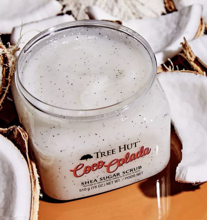 The Coco Colada body scrub surrounded by coconuts.