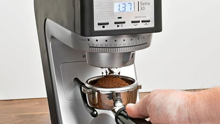 A person grinding beans with a Baratza Sette birr grinder