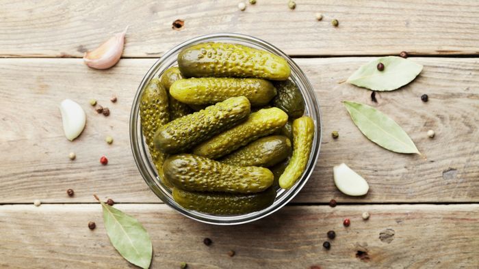 A bowl of pickles placed on a rustic wooden table.