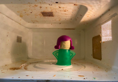 A messy microwave with the cleaner inside.