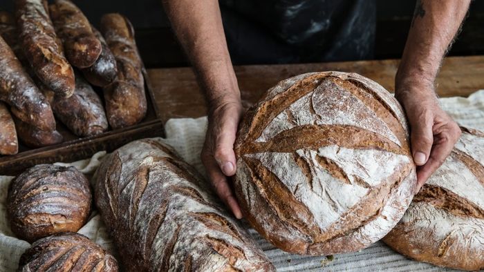 A pair of hands gently cradling a freshly baked loaf of bread.