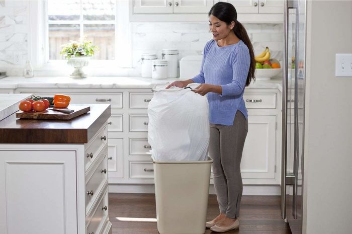 model removing a bulky bag from a kitchen trash can