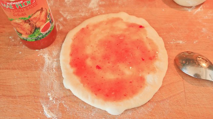 A small pizza topped with sweet chili sauce.