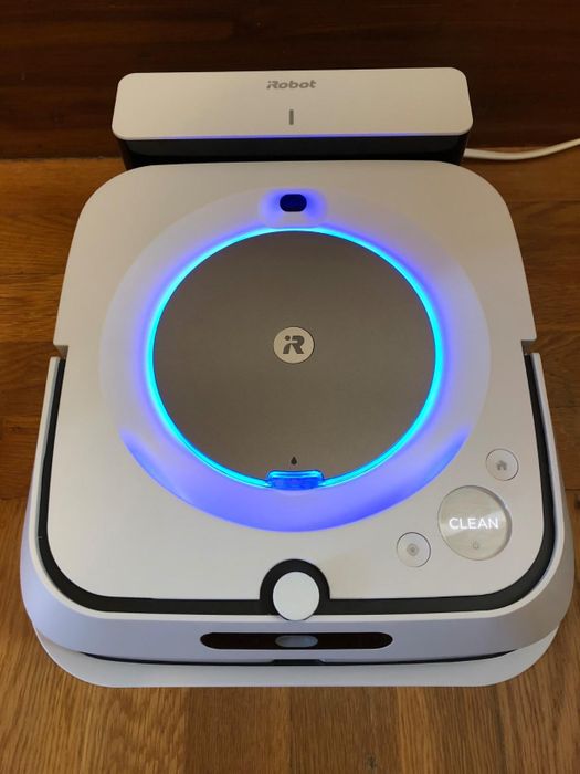 The iRobot vacuum resting on its charging dock, lit up and ready to go.