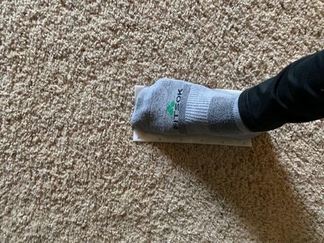 A reviewer stepping on a stain-lifting pad placed on their carpet