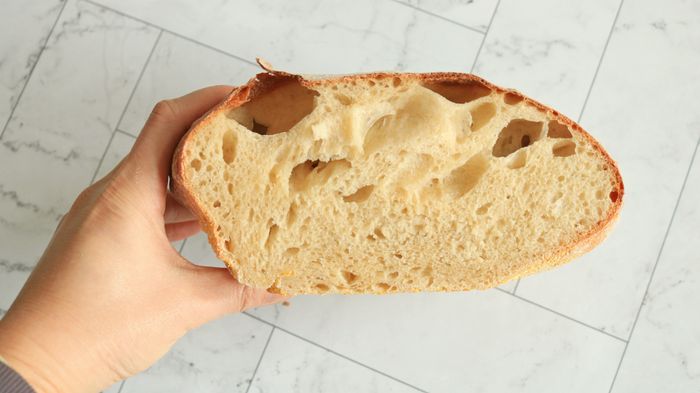 A loaf of bread with irregular shape, sliced in half.