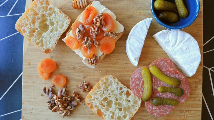 A cheeseboard featuring open-faced sandwiches and a variety of scattered ingredients.