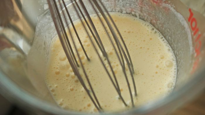 A whisk in a cup filled with custard.