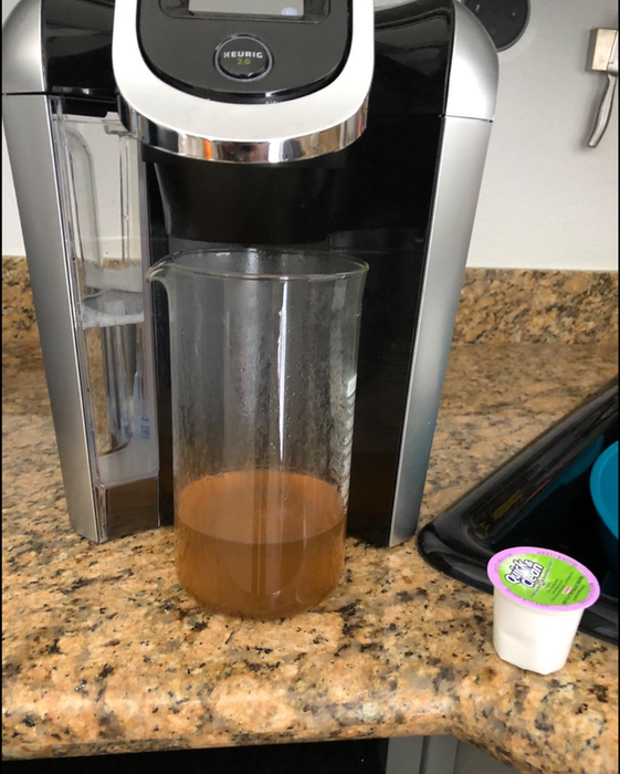 A Keurig cleaning pod next to a dirty stream of water that came out of the machine after a cleaning session.