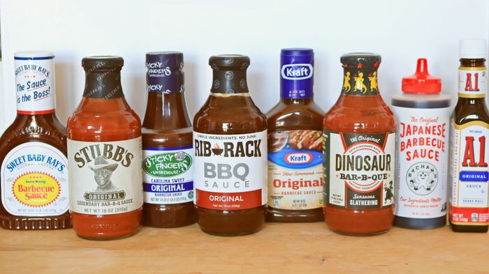 Eight different barbecue sauces arranged on a counter.