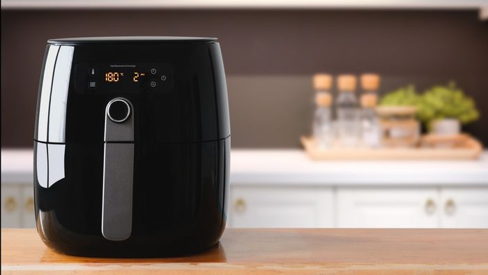A black air fryer resting on a kitchen countertop.