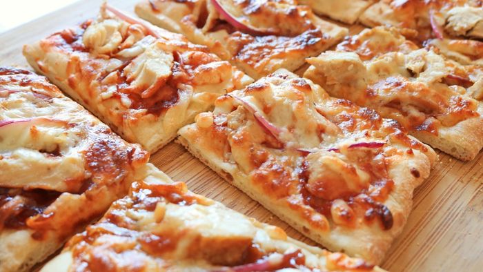 A close-up shot of a pizza, sliced into squares.