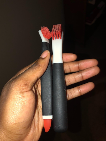The reviewer is holding two pen-sized brushes.
