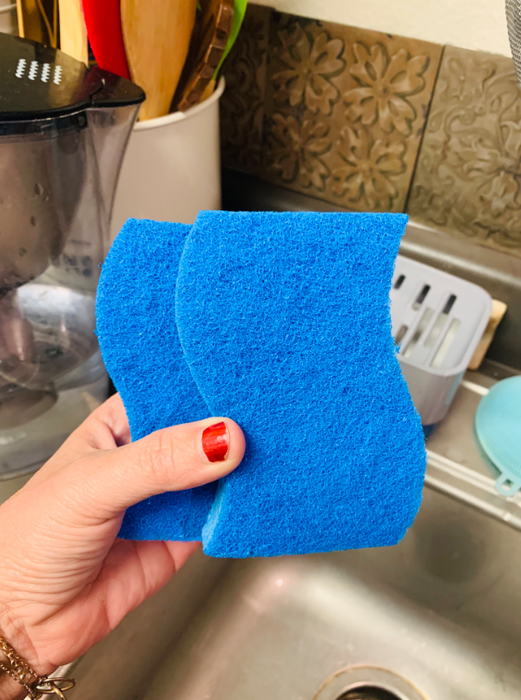 A reviewer holding two sponges above the sink