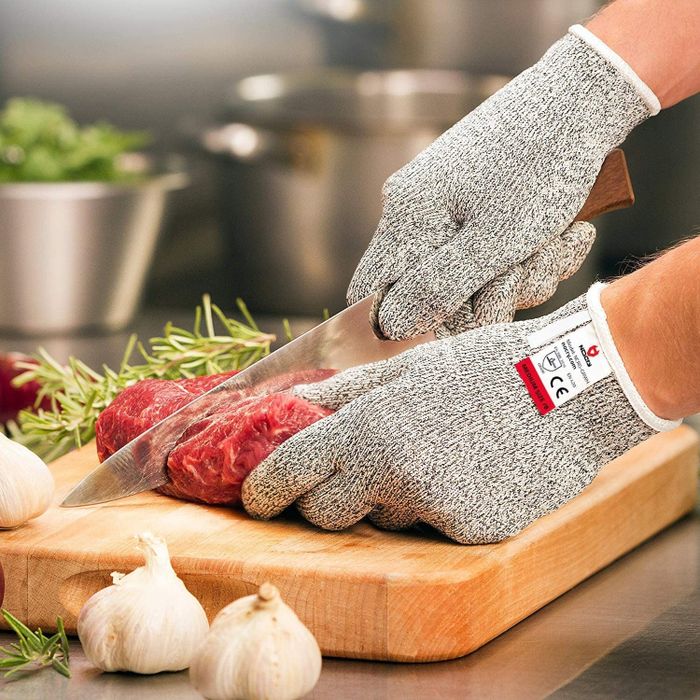 A model carefully cutting meat while wearing the cut-resistant gloves, demonstrating their effectiveness.