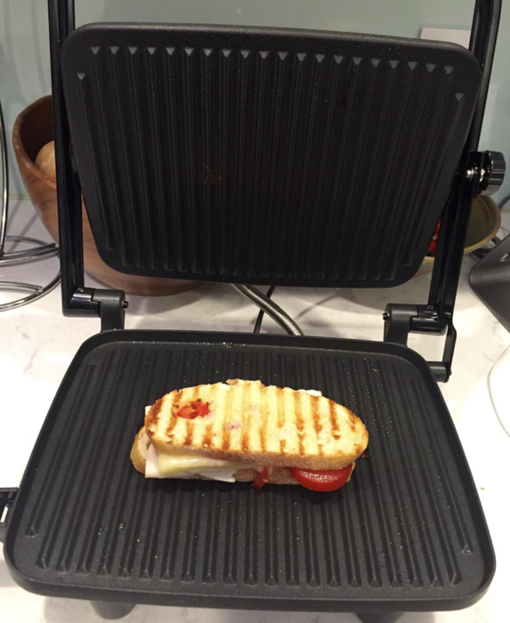 A reviewer putting the panini press grill to work, crafting a perfect sandwich.