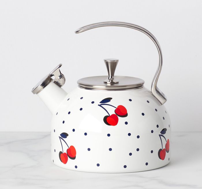 The tea kettle, white with cherries and black dots, is displayed