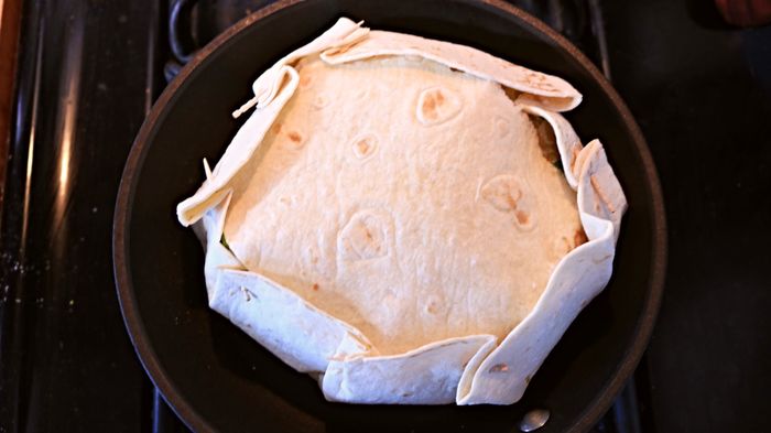 A flour tortilla with toothpicks holding the pleated edges in place.