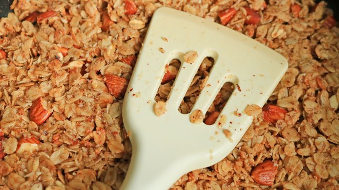 A spatula pressing granola into an even layer.