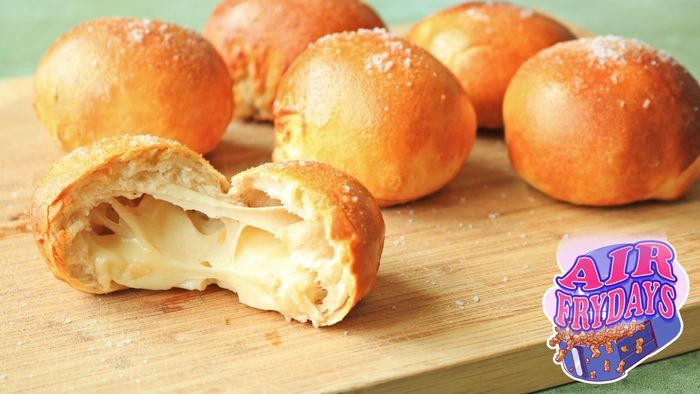 A cheesy biscuit ball split in half with other biscuit balls in the background