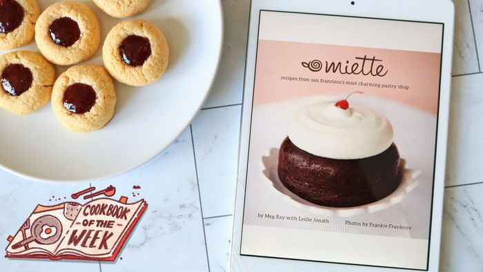 An iPad displaying a cookbook next to a plate of raspberry thumbprint cookies.