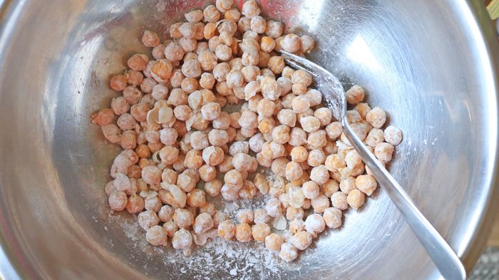 Chickpeas in a bowl, gently coated with white cornstarch powder.