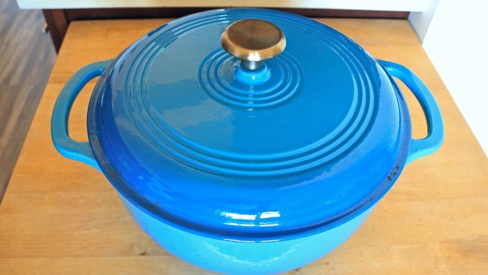 A blue Dutch oven resting on a wooden counter.